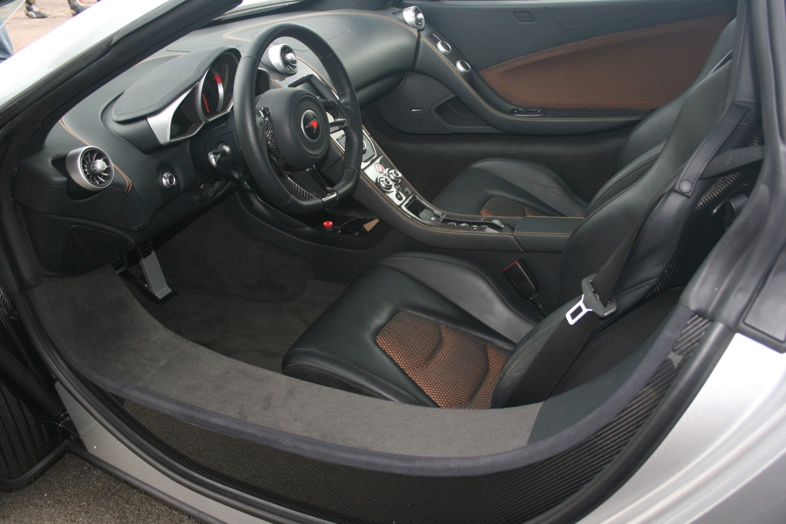 McLaren MP4-12C interior showing woven carbon-fiber steering-wheel spokes and leather rim