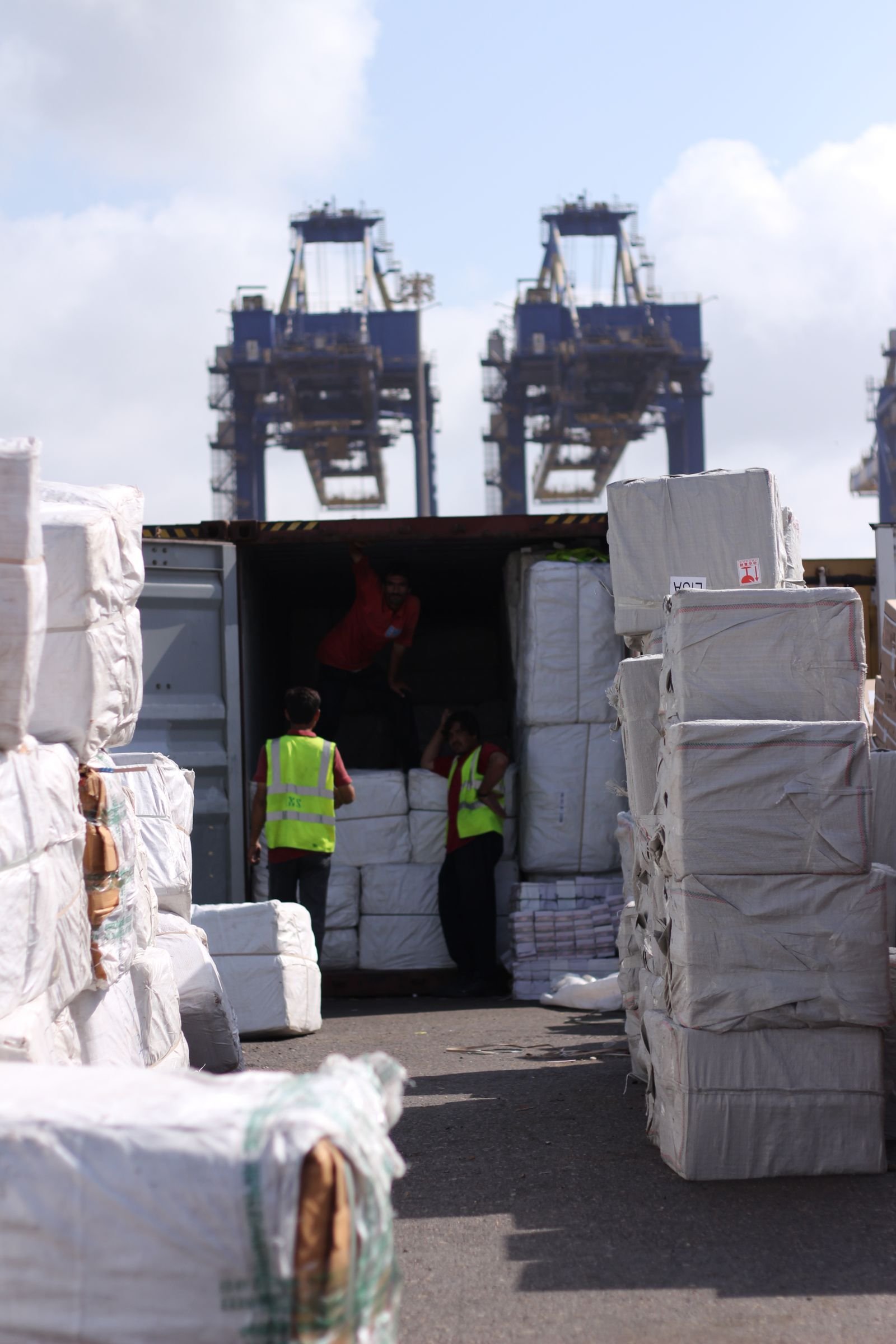 Real port workers loading protected cargo into a shipping container — illustrative logistics photograph