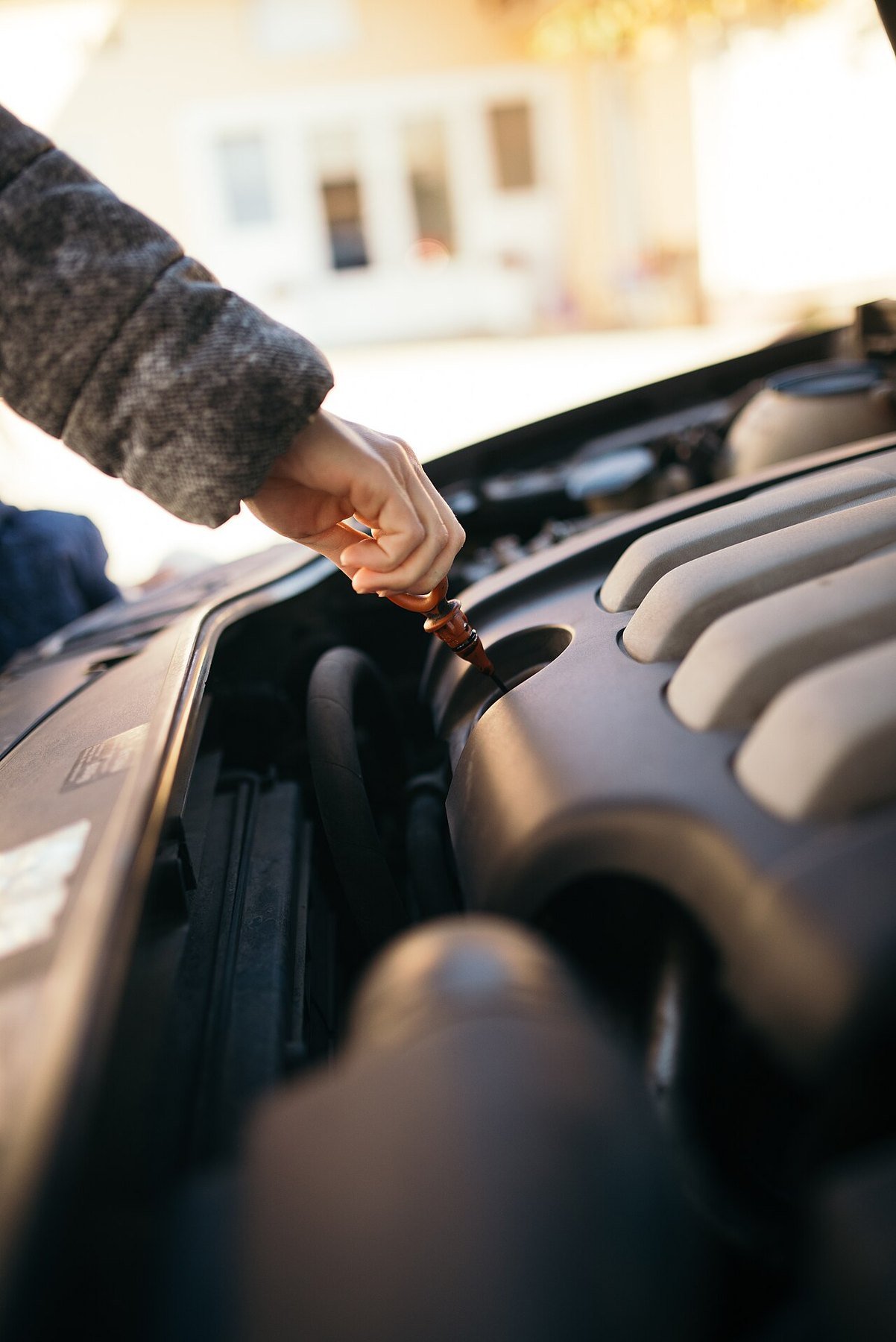 Real photograph of a person checking engine oil under an open car hood