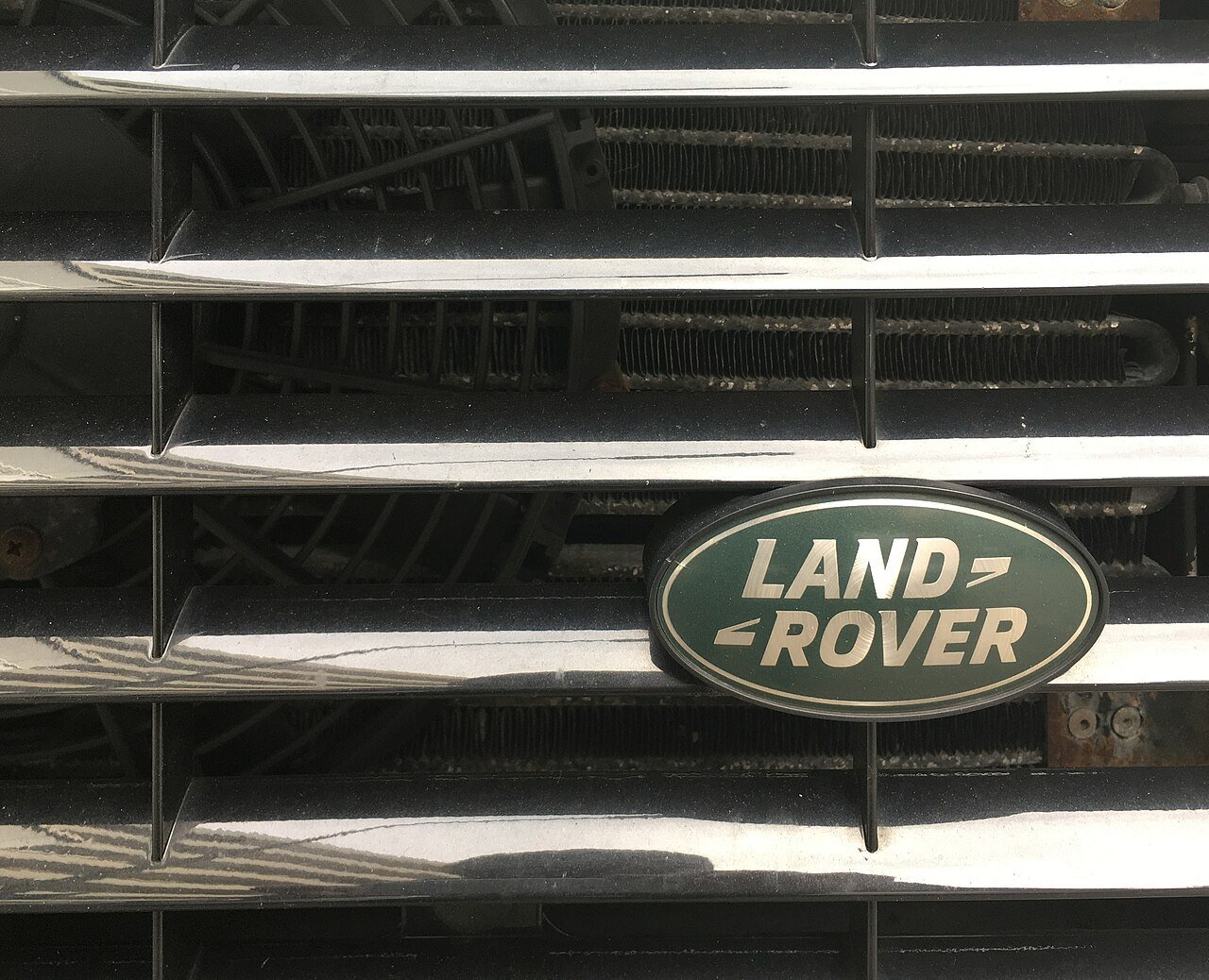 Real close-up photograph of a Land Rover Defender grille and cooler behind it