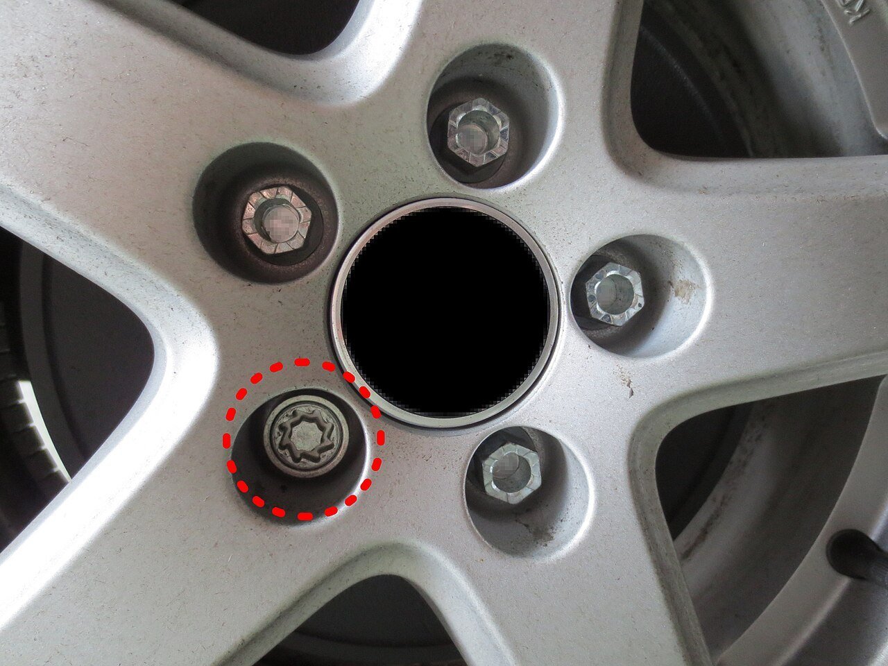 Real close-up photograph of an alloy wheel with wheel-lock hardware